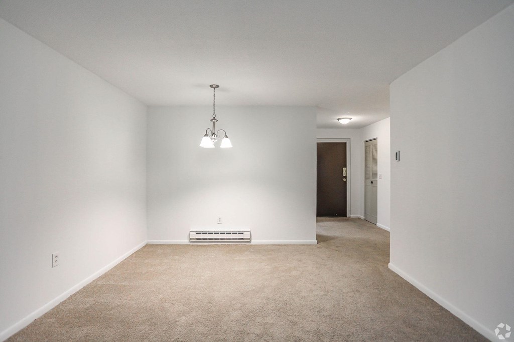 A room with a carpet floor and a hanging light fixture.