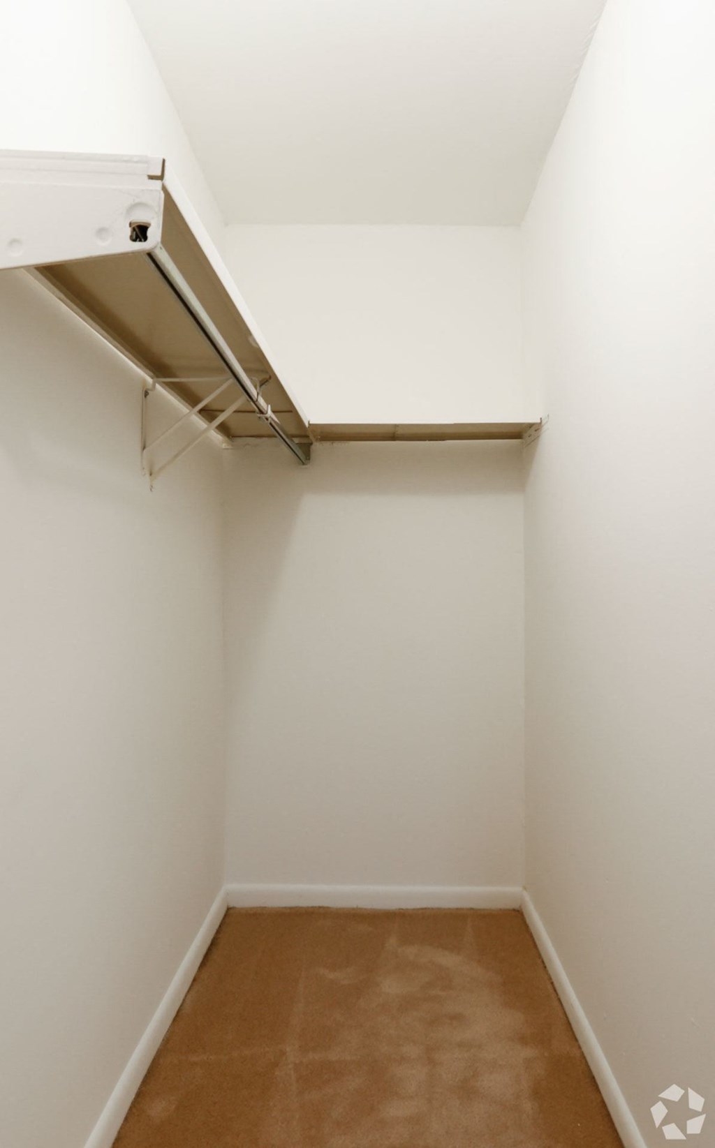 Large oversized closets, extra storage room, with a shelf and a light brown floor.