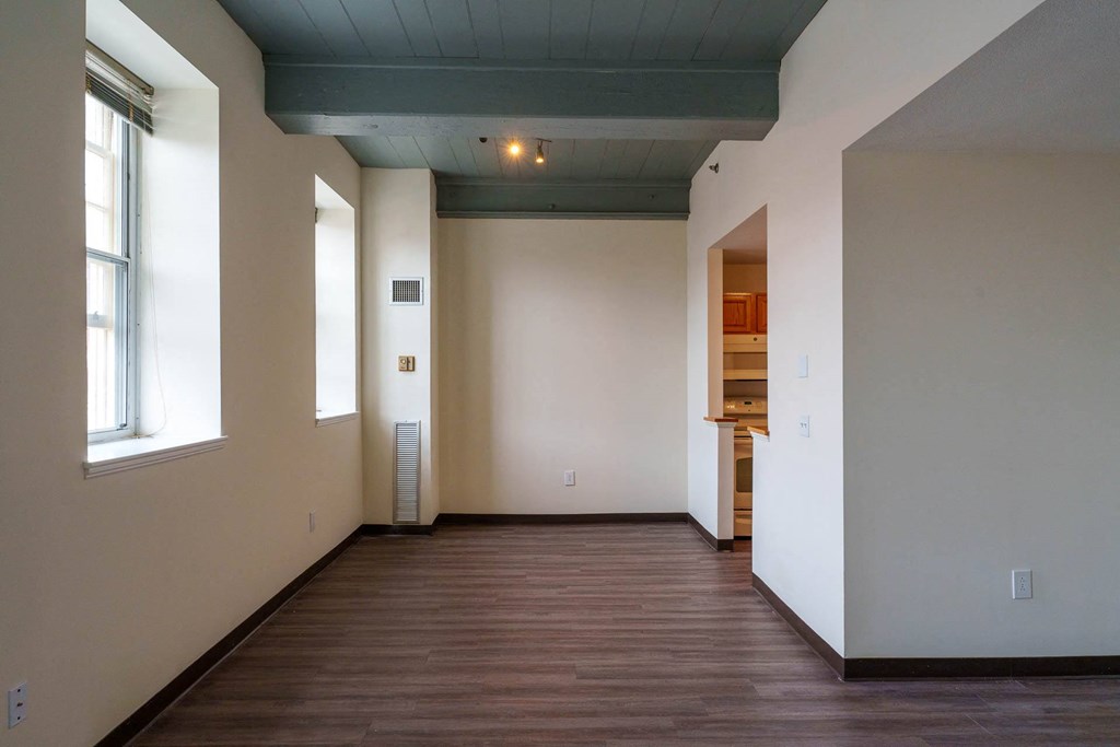 A room with a wooden floor and a window on the left side.