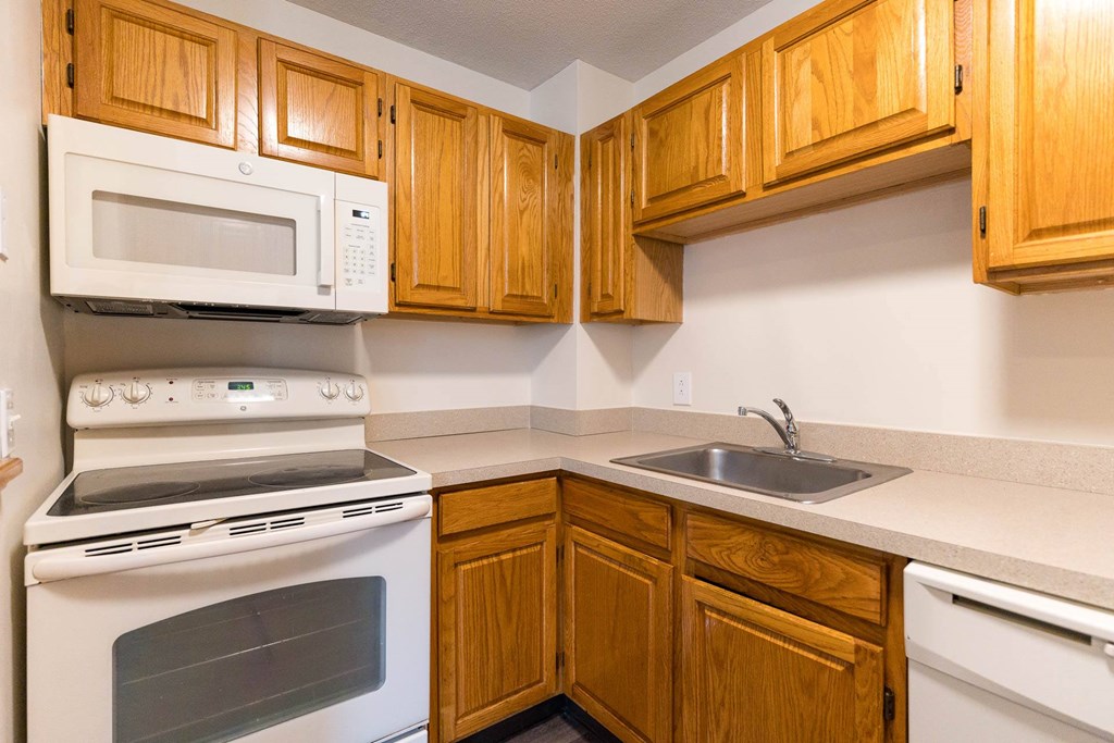 A kitchen with wooden cabinets and a white oven.