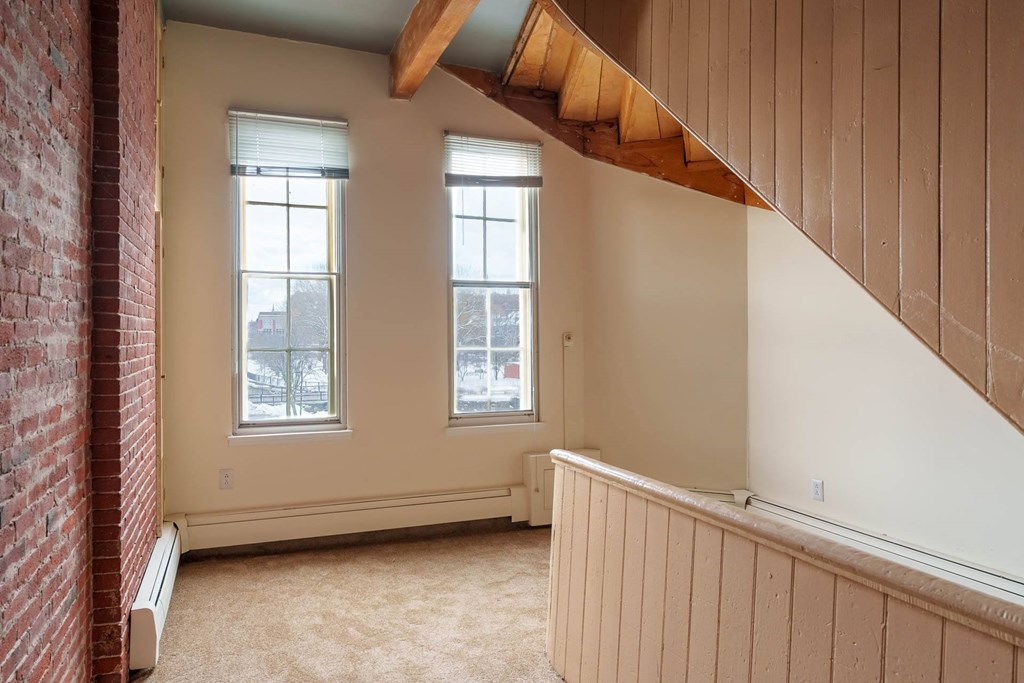 A room with a red brick wall and a wooden beam ceiling.