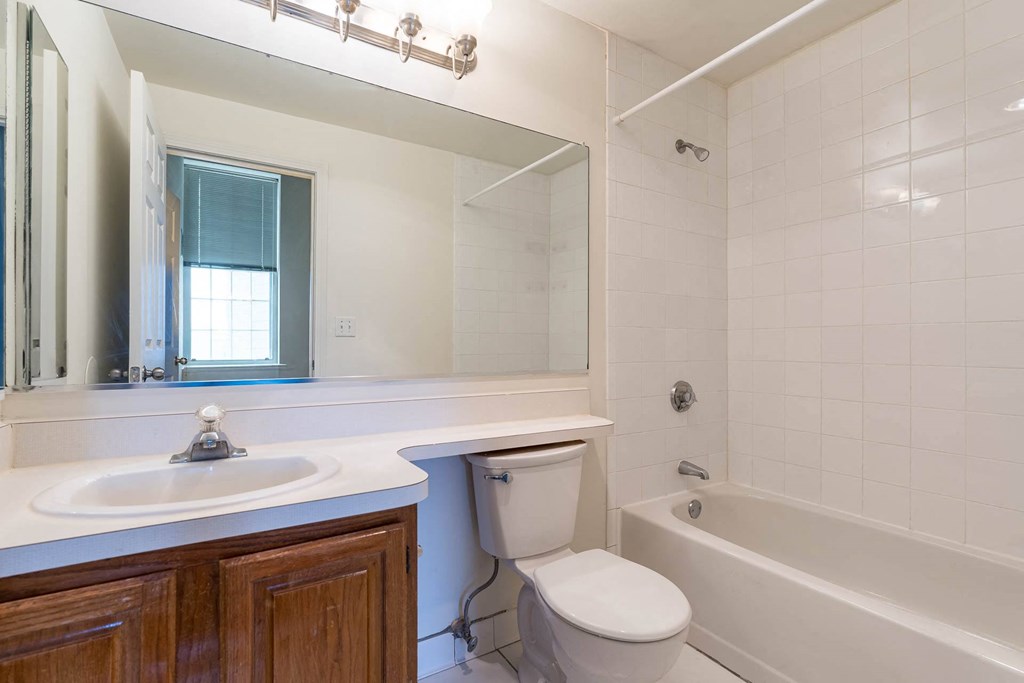 A white toilet sits in a bathroom next to a sink and a bathtub.