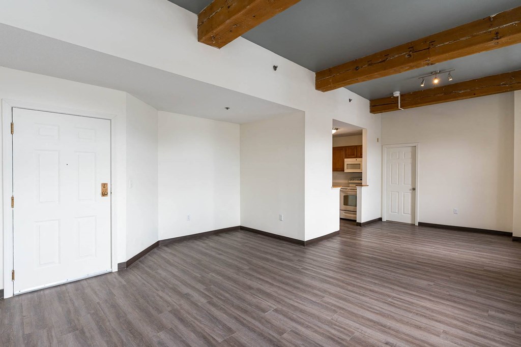 A room with a white door and wooden beams on the ceiling.