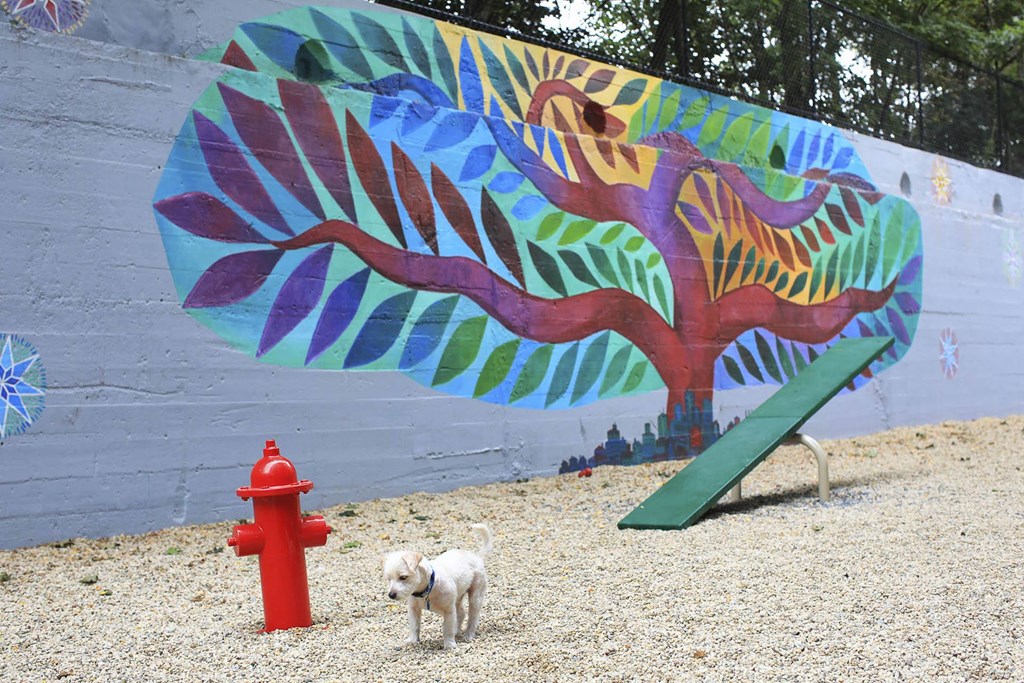 a dog standing next to a fire hydrant in front of a mural