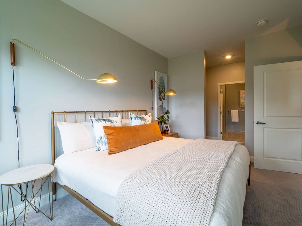 A serene bedroom with a queen-size bed, decorative pillows, a nightstand, and soft lighting for a cozy ambiance.