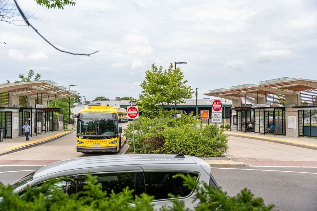 A bus is driving down a street past a bus stop.