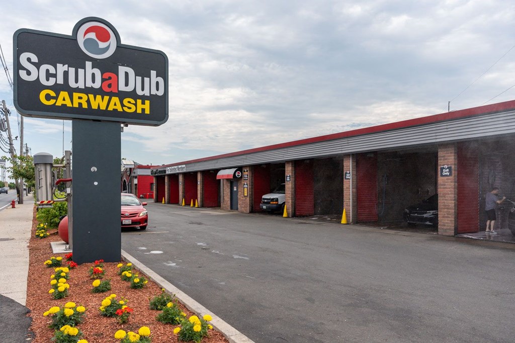 A Scrubadub Carwash sign is in front of a car wash.