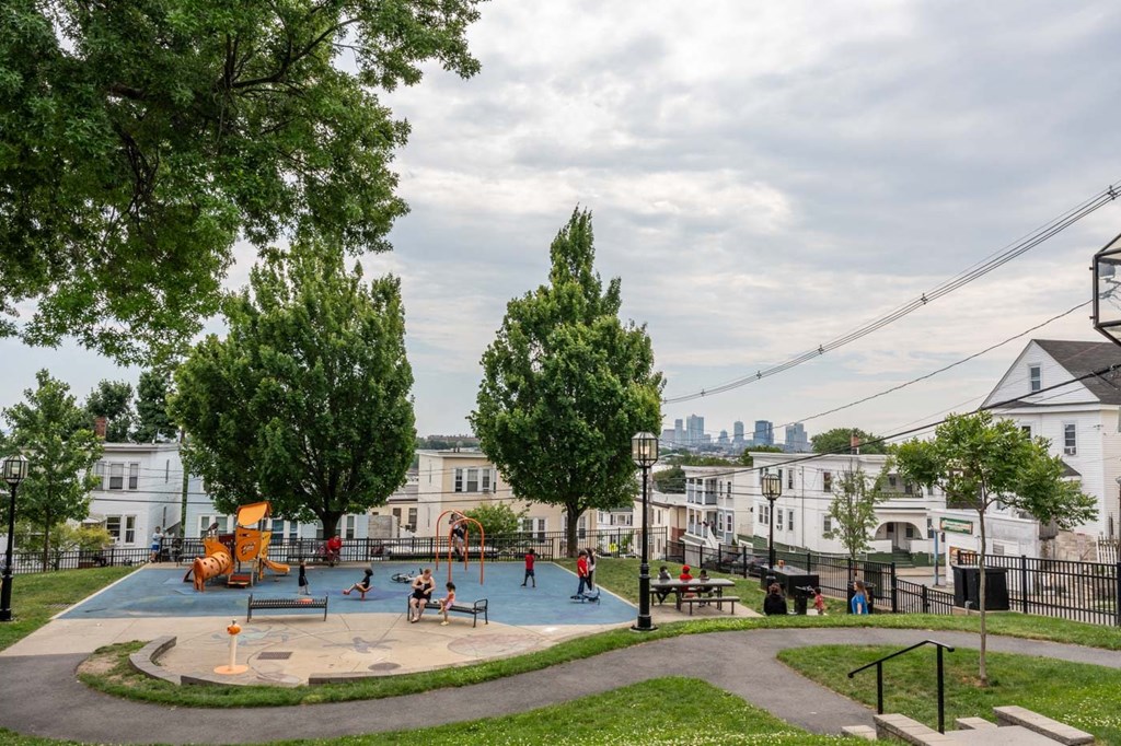 A playground with a slide and swings surrounded by trees and a fence.