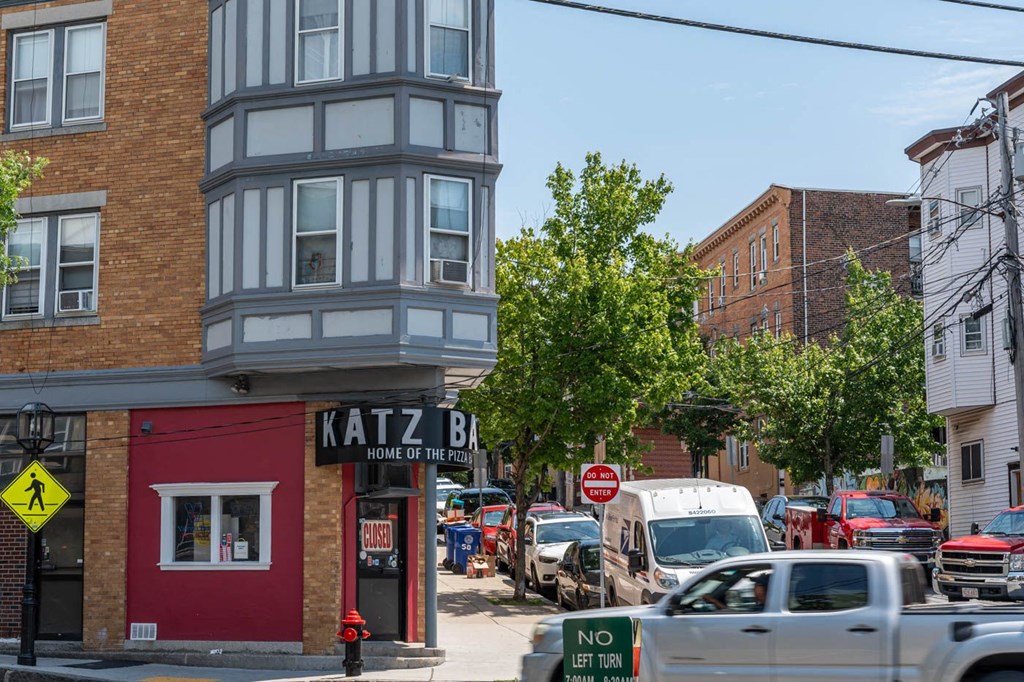 A street view with a red building on the left and a sign that says