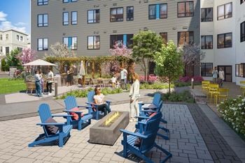 A group of people are sitting around a fire pit on a patio.