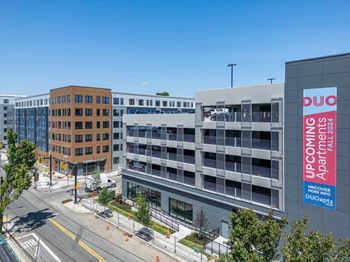 A street view of a building with a sign that reads "UPCOMING UNICOVERSITY APARTMENTS DUOO 024".
