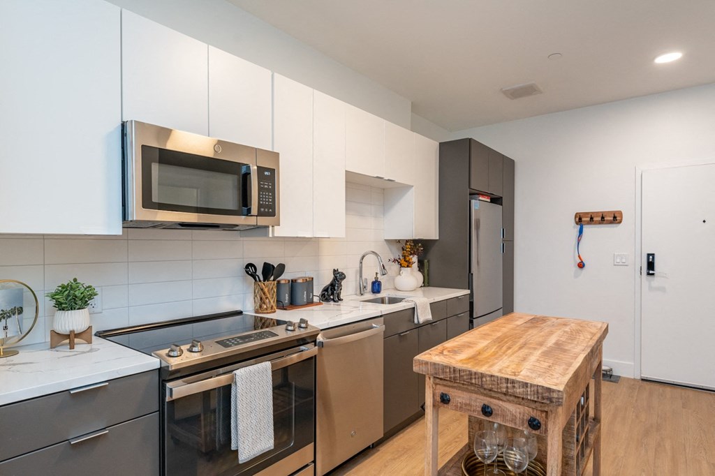 A modern kitchen with a wooden table and stainless steel appliances.