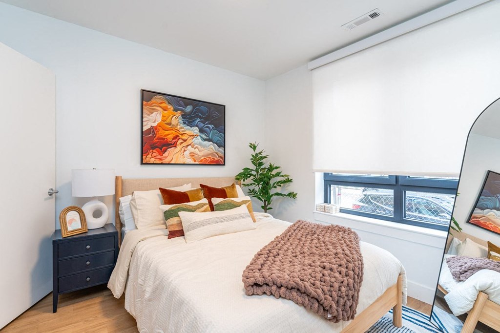 A bedroom with a bed, a nightstand, and a painting on the wall.