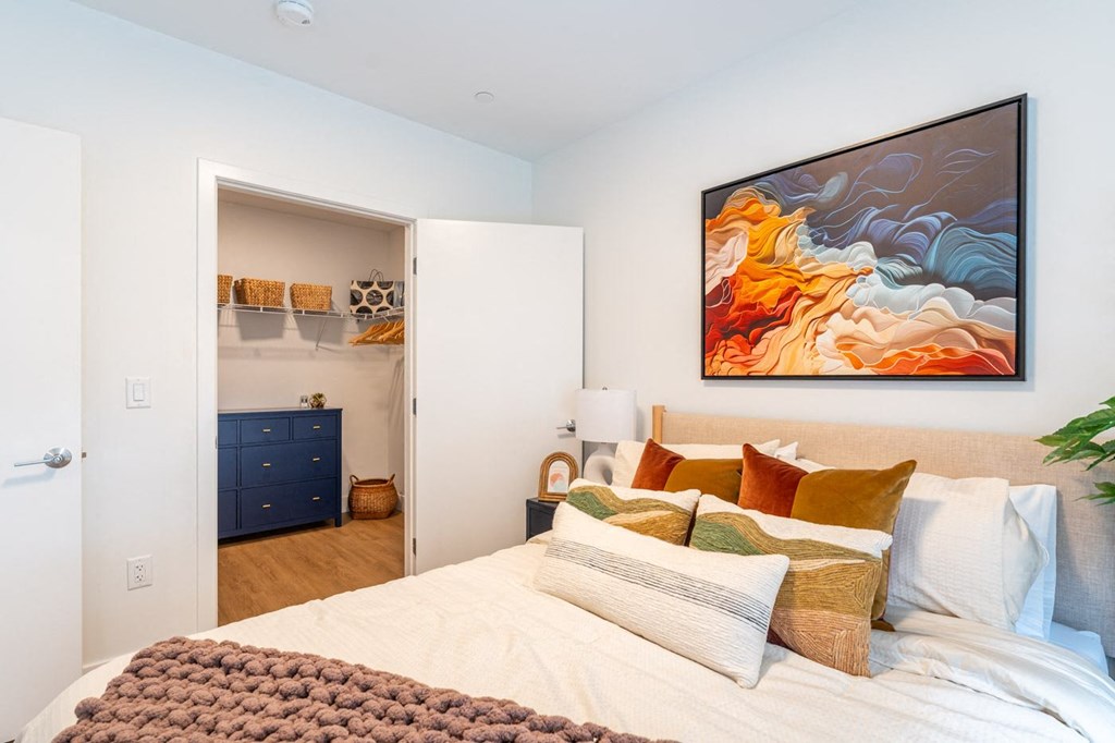 A bedroom with a large bed and a painting on the wall.