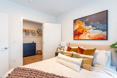 A bedroom with a large bed and a painting on the wall.