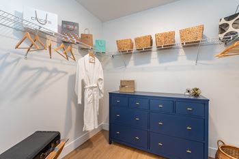 A white robe is hanging on a rack in a room with a blue dresser.