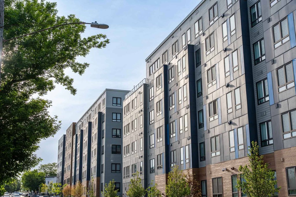 A row of modern apartment buildings with trees in front.