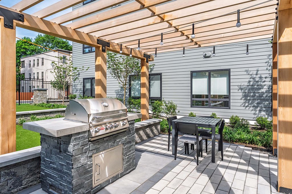 A modern outdoor kitchen with a grill and table.