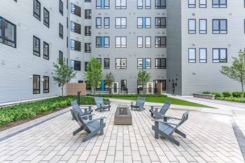 A modern courtyard with benches and a tree in front of a building.