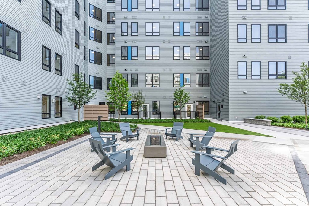 A modern courtyard with benches and a tree in front of a building.