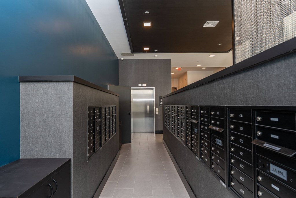 A hallway with a row of mailboxes on the right and a door in the middle.