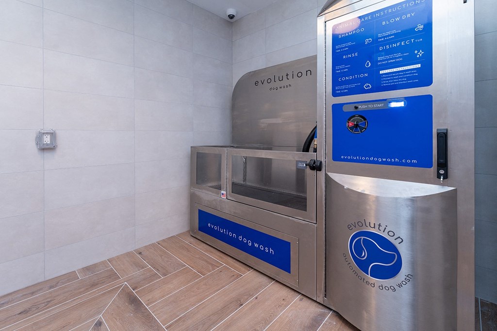 A stainless steel dog wash station with a blue sign that says