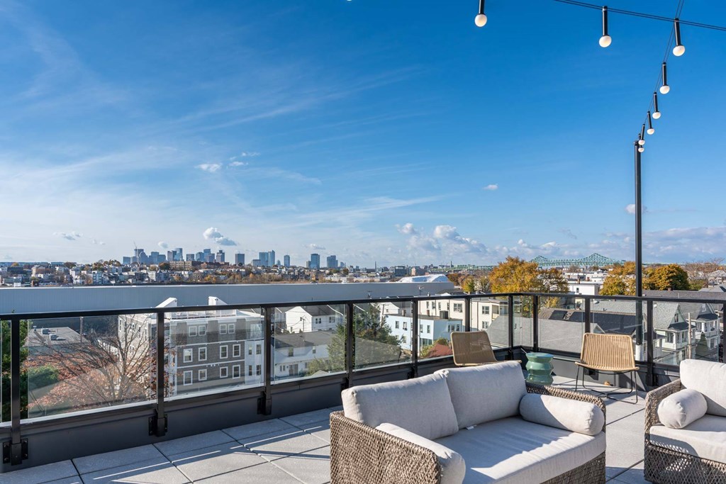 A balcony with a white couch and a view of a city skyline.