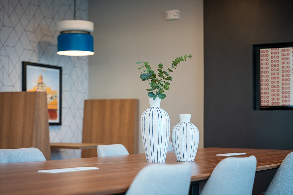 A dining table with two vases and a plant on it.