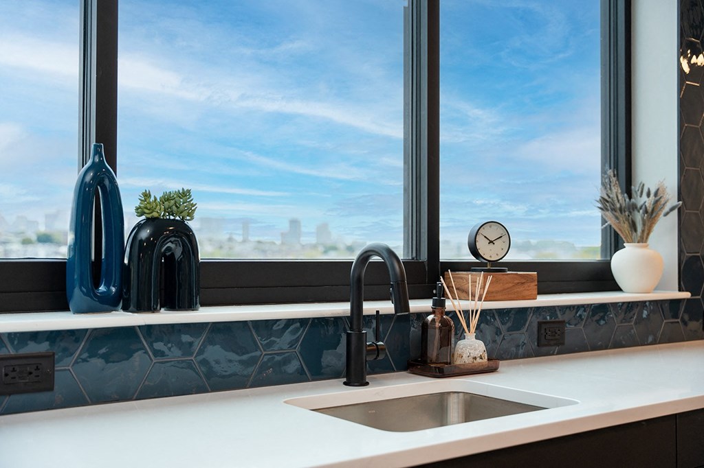 A kitchen with a large window overlooking a cityscape.