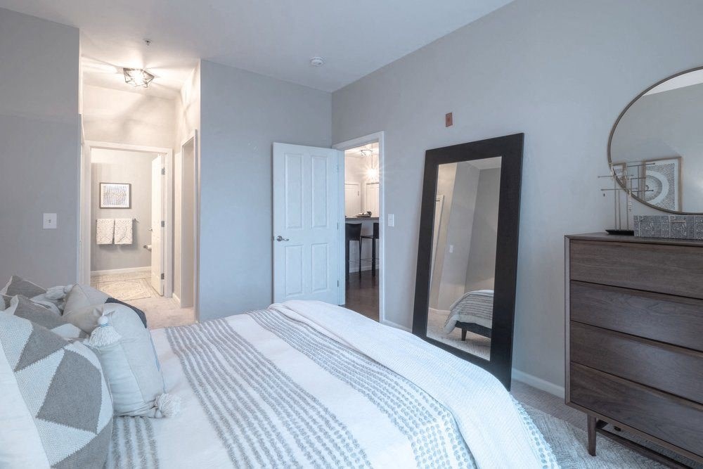 a bedroom with a large bed and a dresser with a mirror