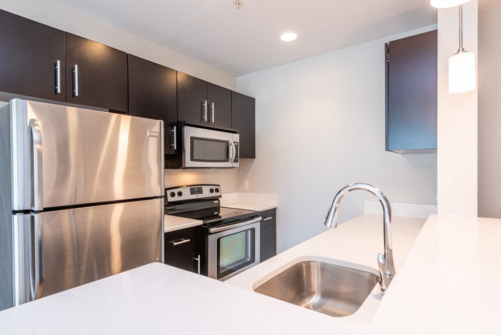 kitchen with stainless steel refridgerator, quartz counters, oven and microwave