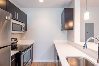 Aparttment kitchen, dark cabinets, oven, refrigerator, stainless steel