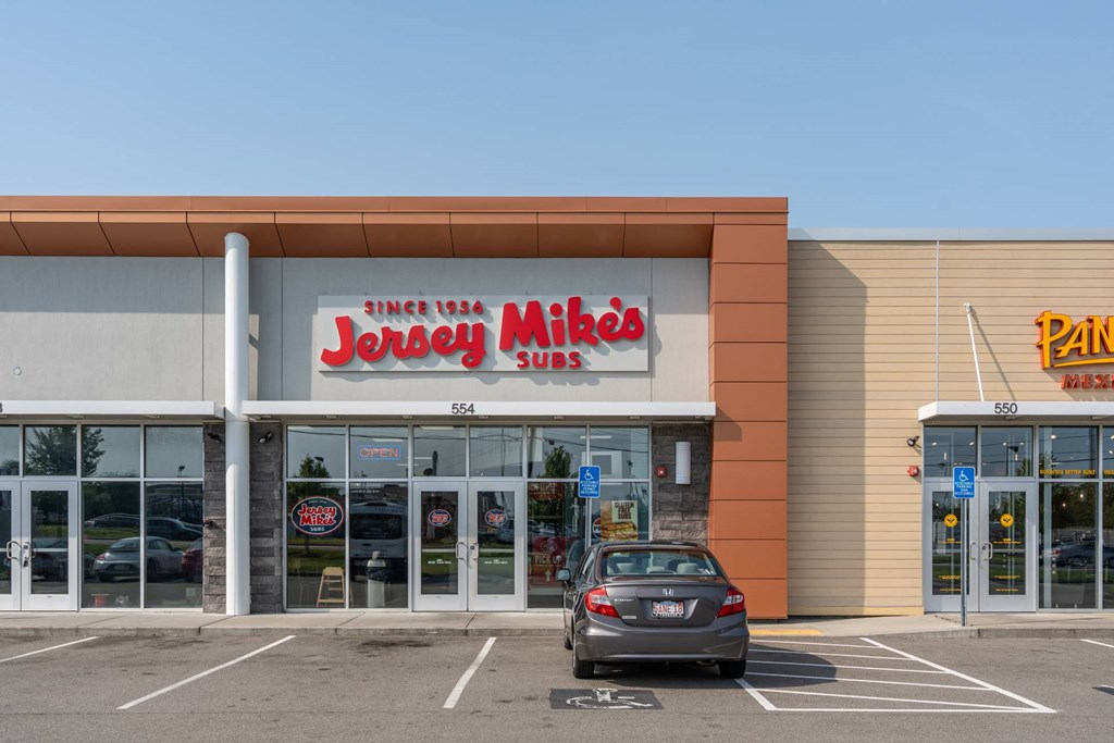 A car is parked in front of a store with a red and white sign that says
