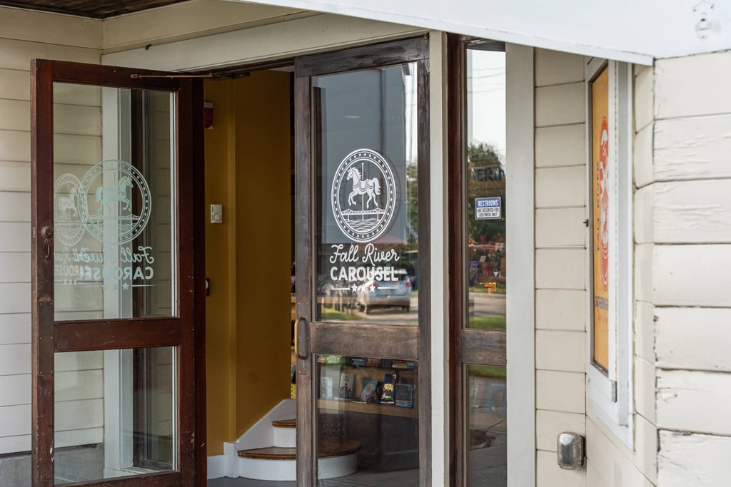 Close-up of the Fall River Carousel entrance door, featuring white horse logo etched on glass.