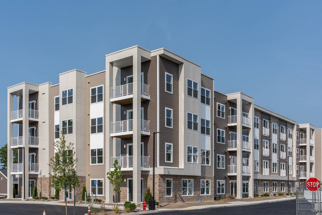 Four-story apartment building at Slade Farm Residences with mixed tan siding, stone base accents and multiple balconies.