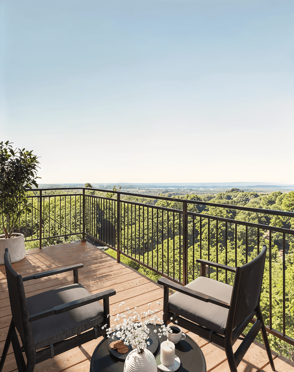 A balcony with two chairs and a table with a vase of flowers on it.
