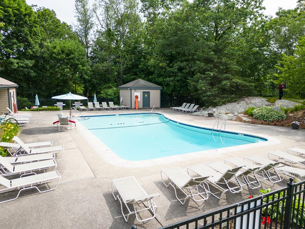 a swimming pool with chaise lounge chairs and trees in the background