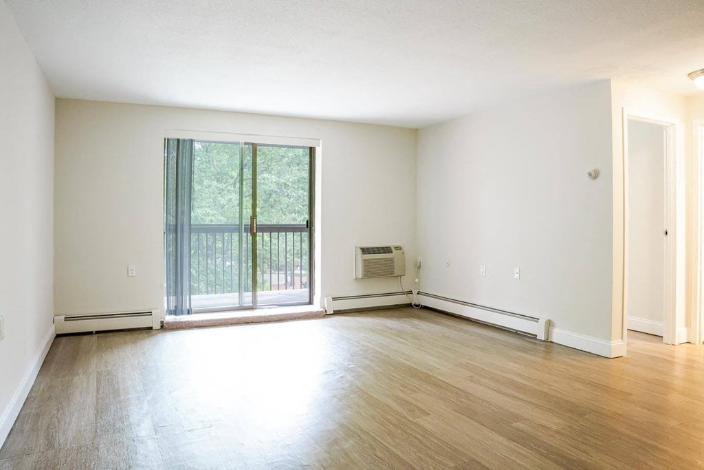 an empty living room with hardwood floors and a sliding glass door