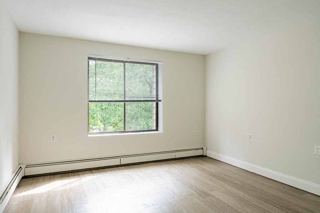 a bedroom with hardwood floors and a large window