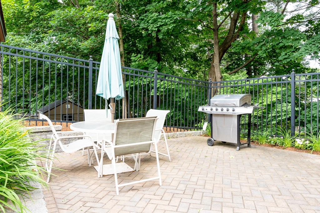 a patio with a table and chairs and a grill