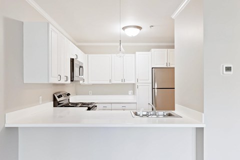 A white kitchen with a sink and cabinets.