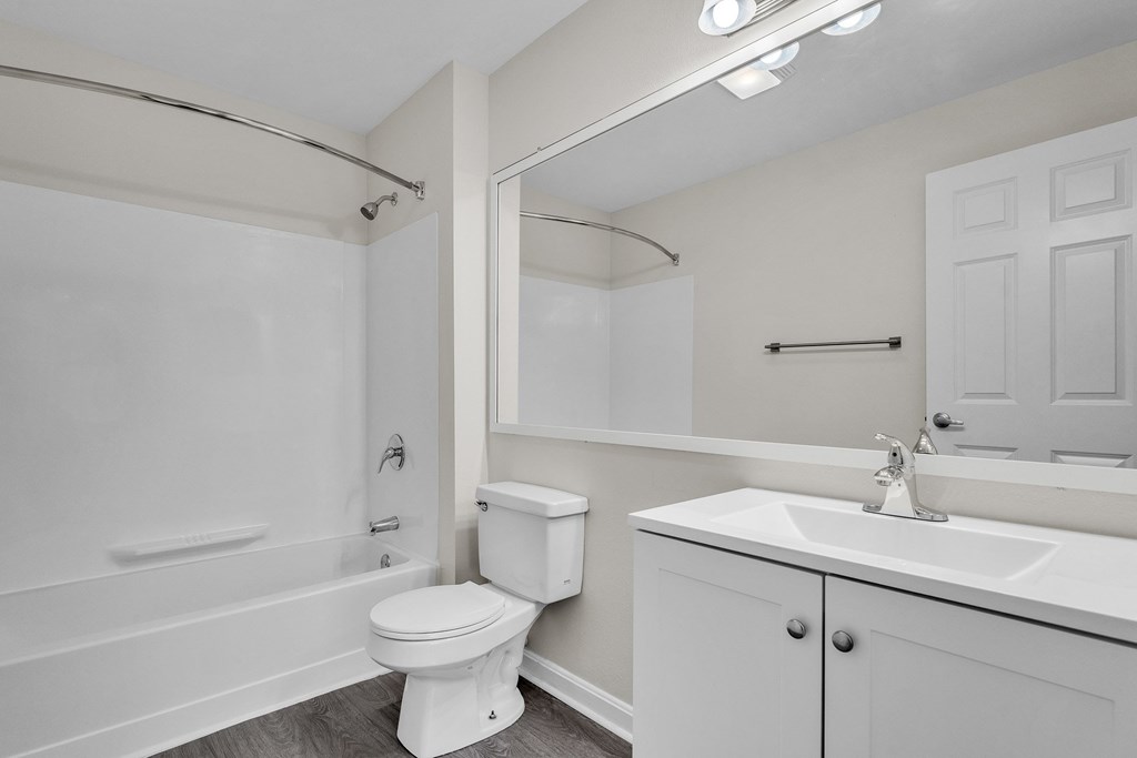 A white bathroom with a toilet, sink, and bathtub at the Ledges Apartments in Weymouth.