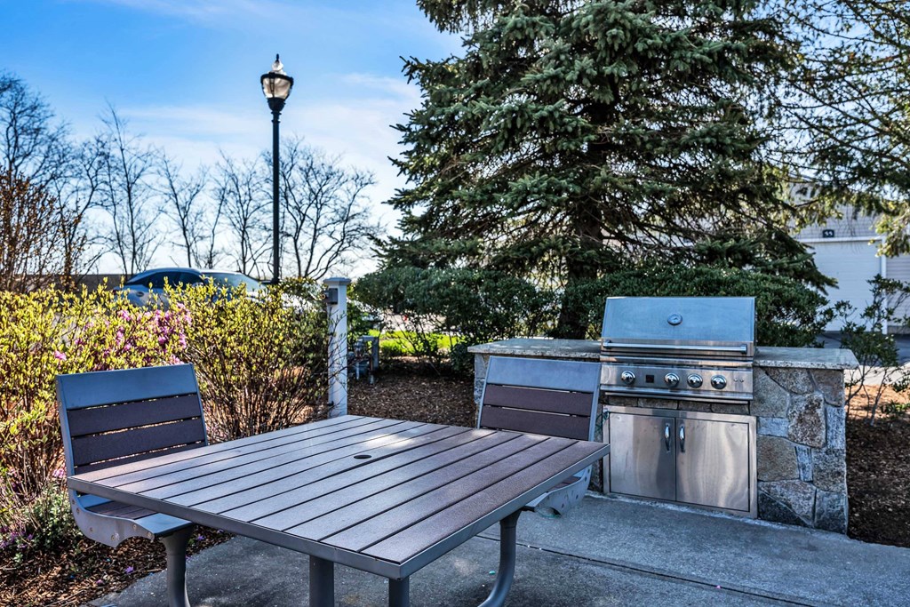 A picnic table is in front of a grill at the Ledges Apartments.