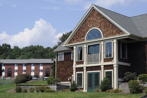 A red brick house with a green door and windows.
