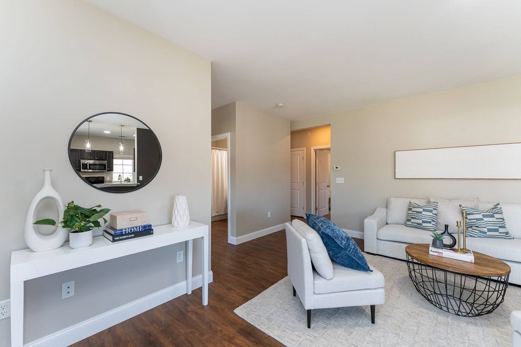 A living room with a white couch, a coffee table, and a mirror on the wall.