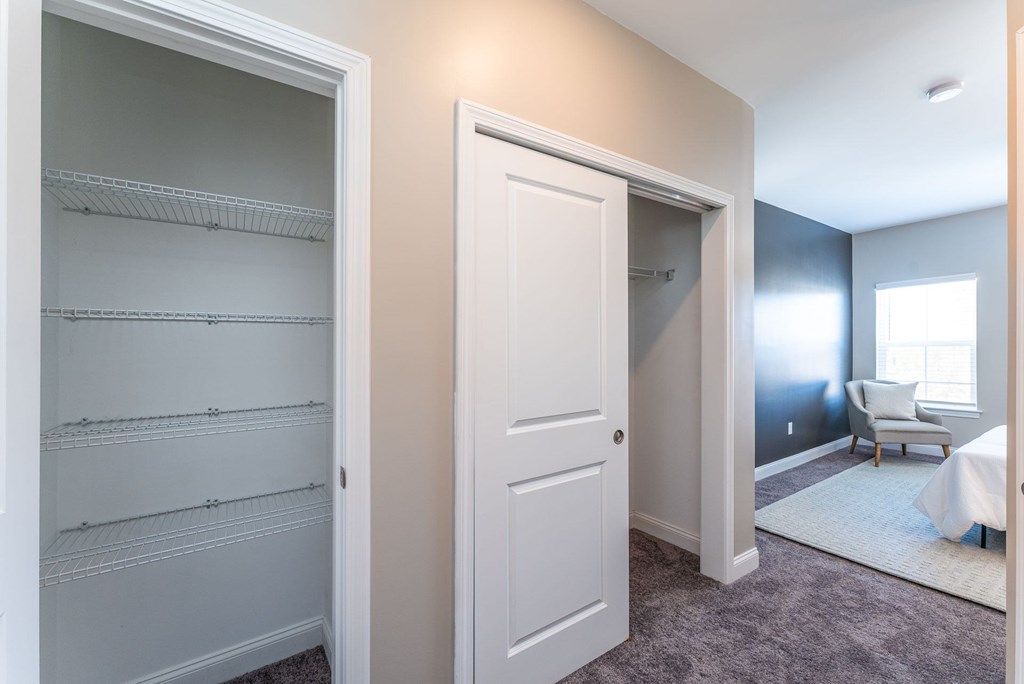 A white closet with shelves and a white door.