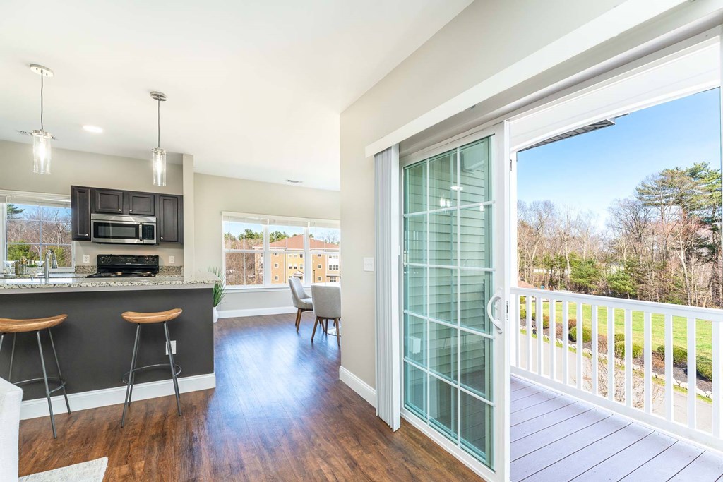 A modern kitchen with a bar area and a view of the backyard through a glass door.