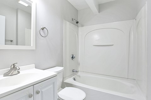 A white bathroom with a toilet, sink, and bathtub.
