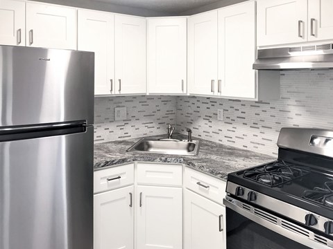 A kitchen with white cabinets and a stainless steel refrigerator.