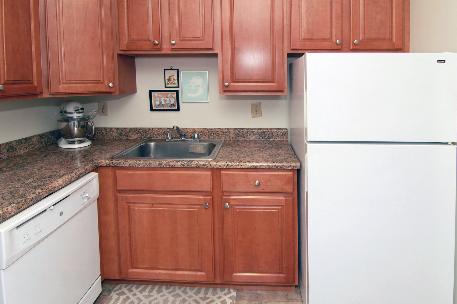 A kitchen with brown cabinets and a white fridge.